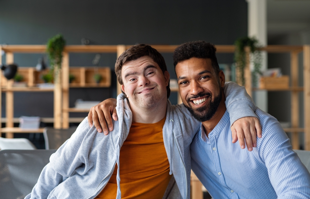 One man with down syndrome with a second man both smiling