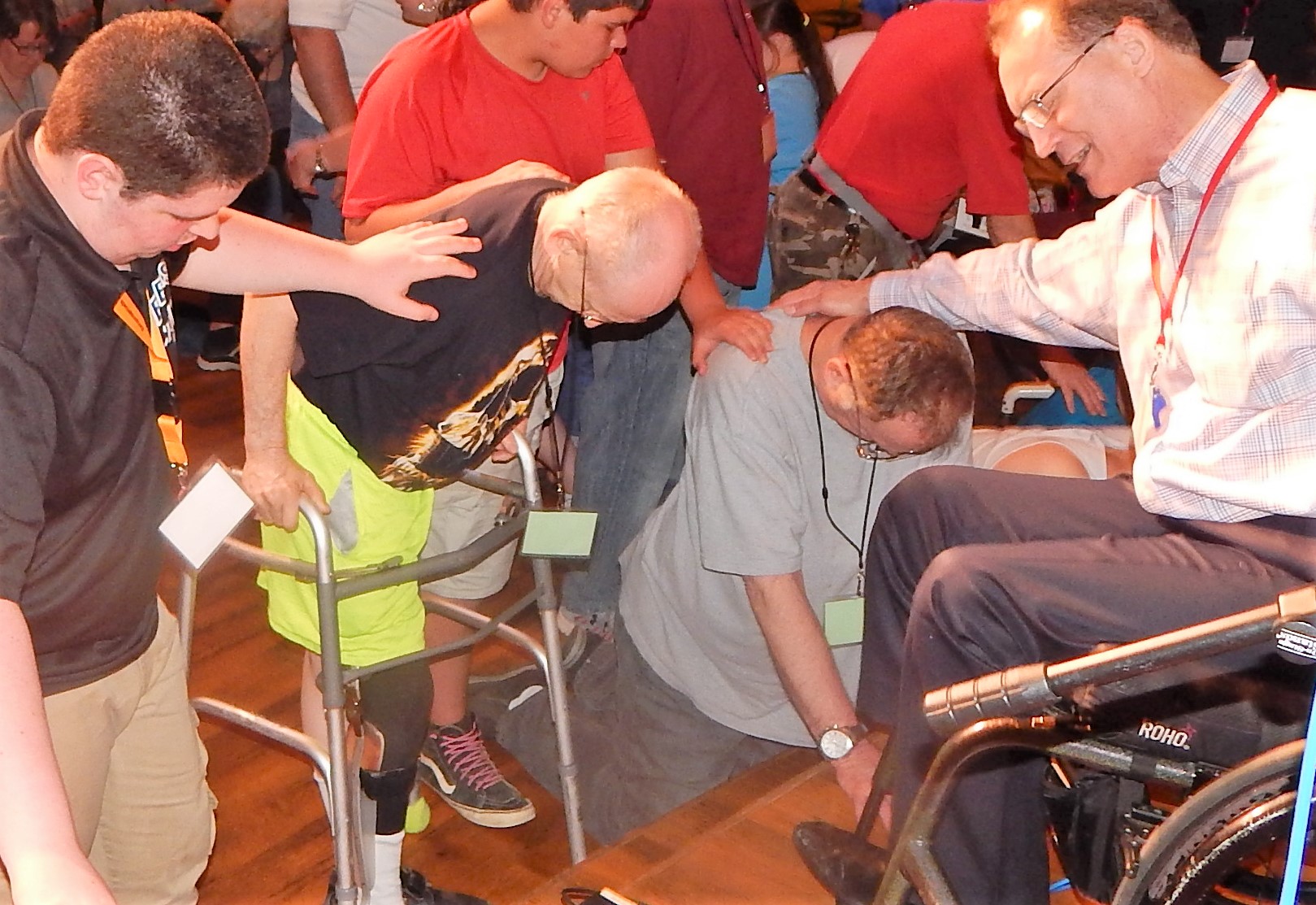 A group of people some using walkers and wheelchairs praying together at the alter