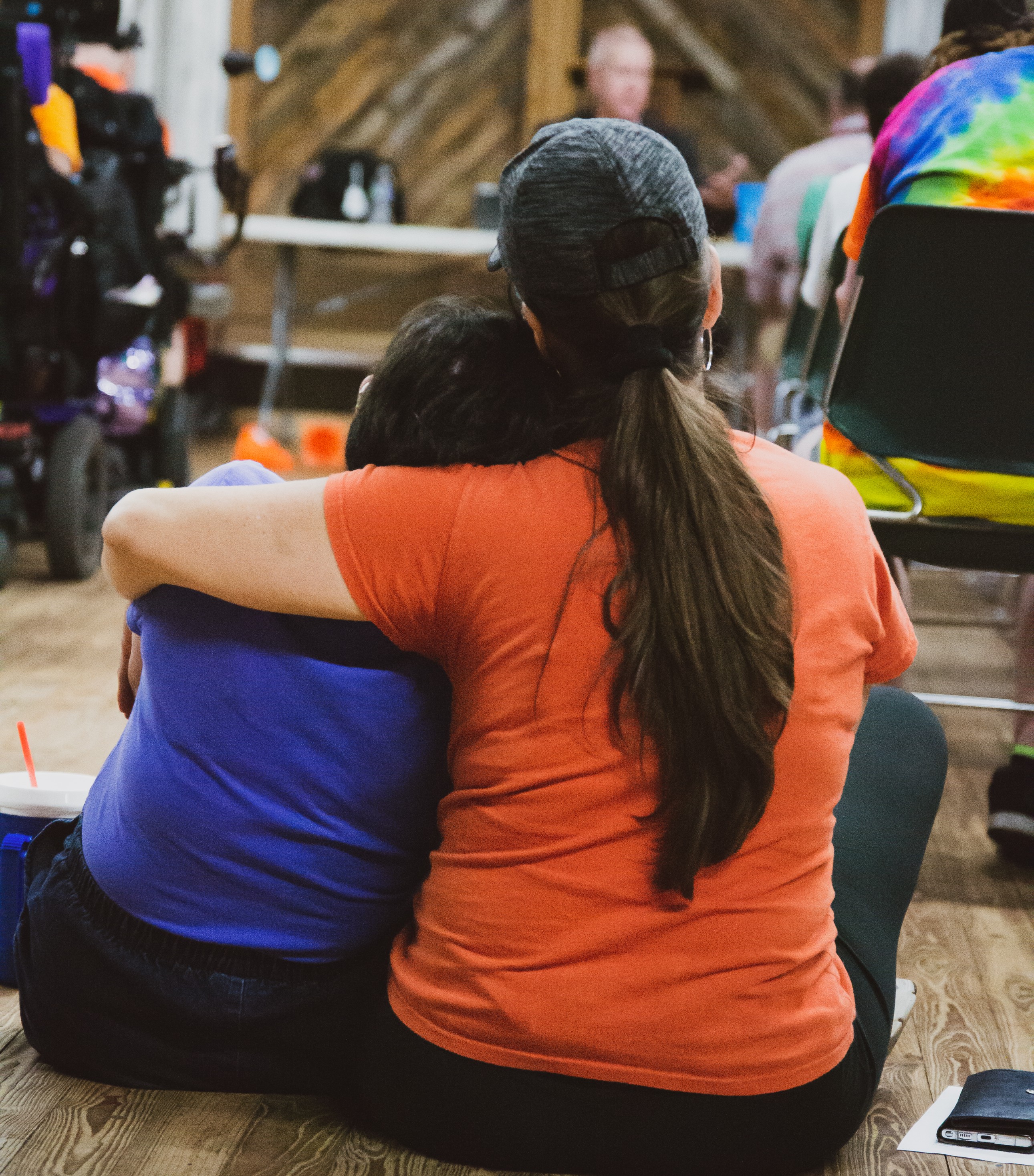 Two people shown from behind, one with their arm wrapped around the other, looking as if giving emotional support