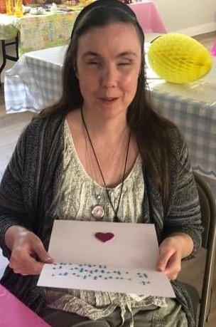 lady smiling while holding the braille card open