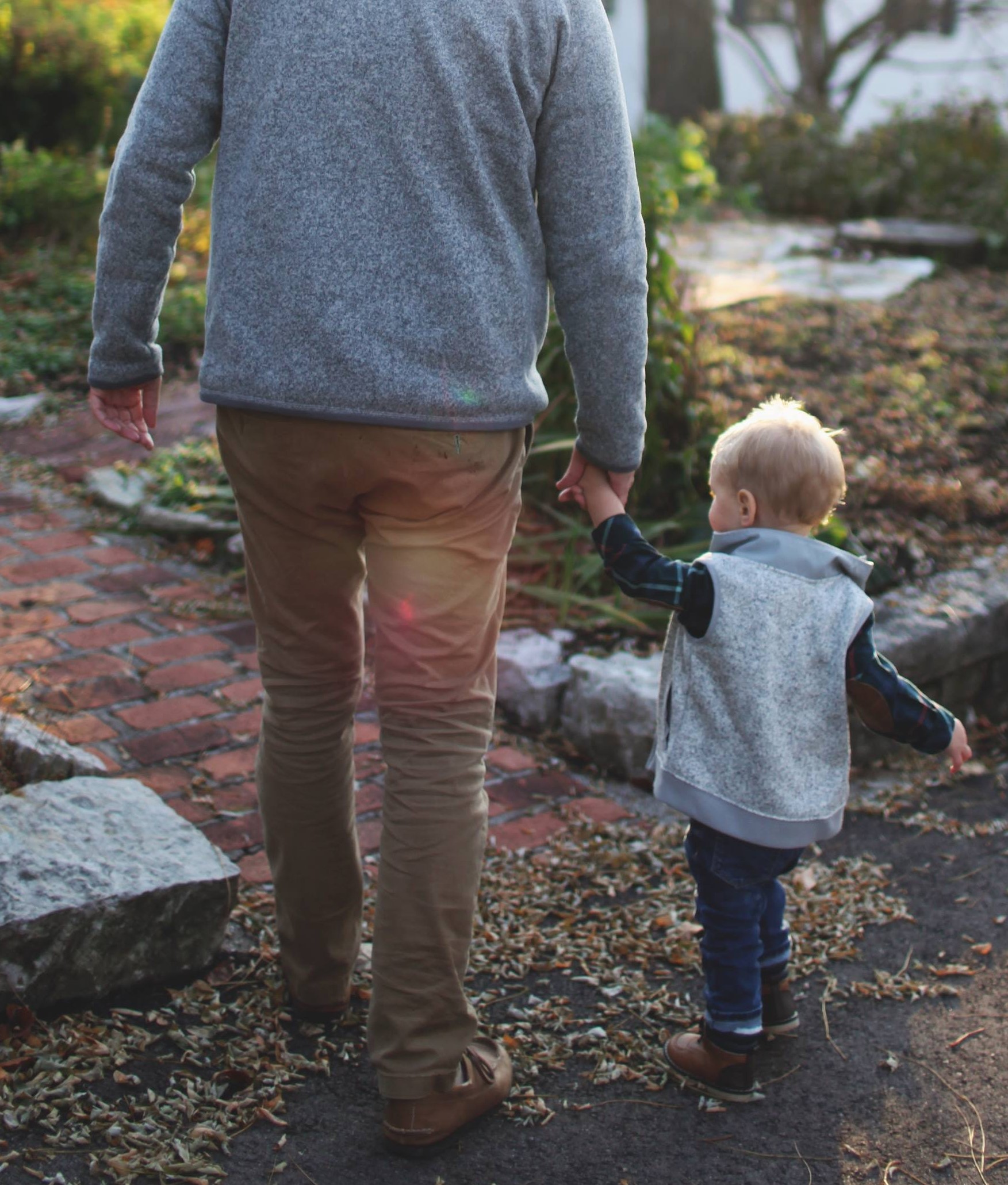 Man taking a boy by the hand and walking alongside him