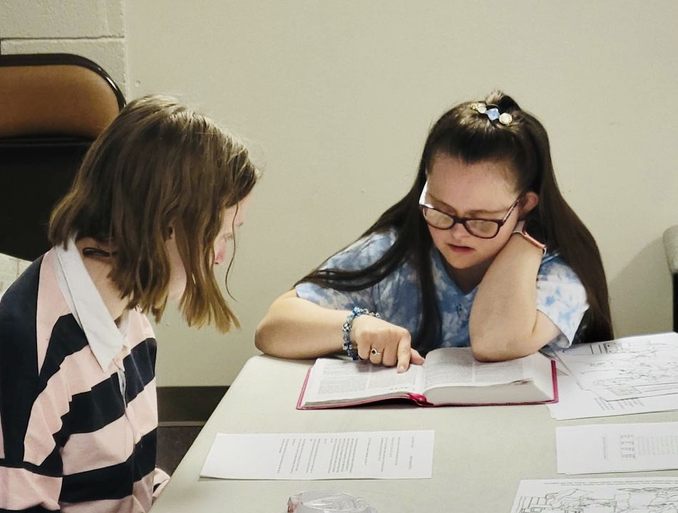 Two girls one reading a bible