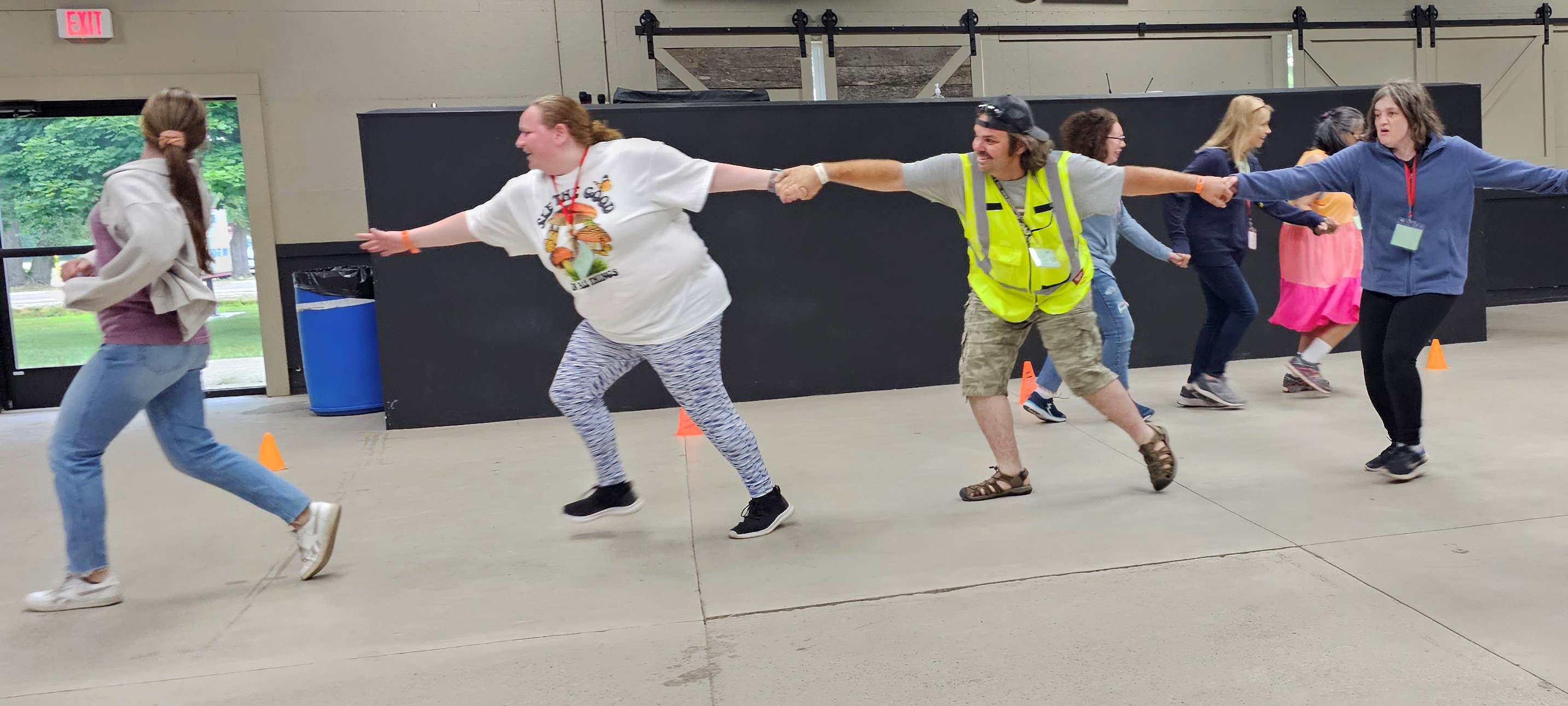 A group of people holding hands while stepping to catch up with another girl in front of them