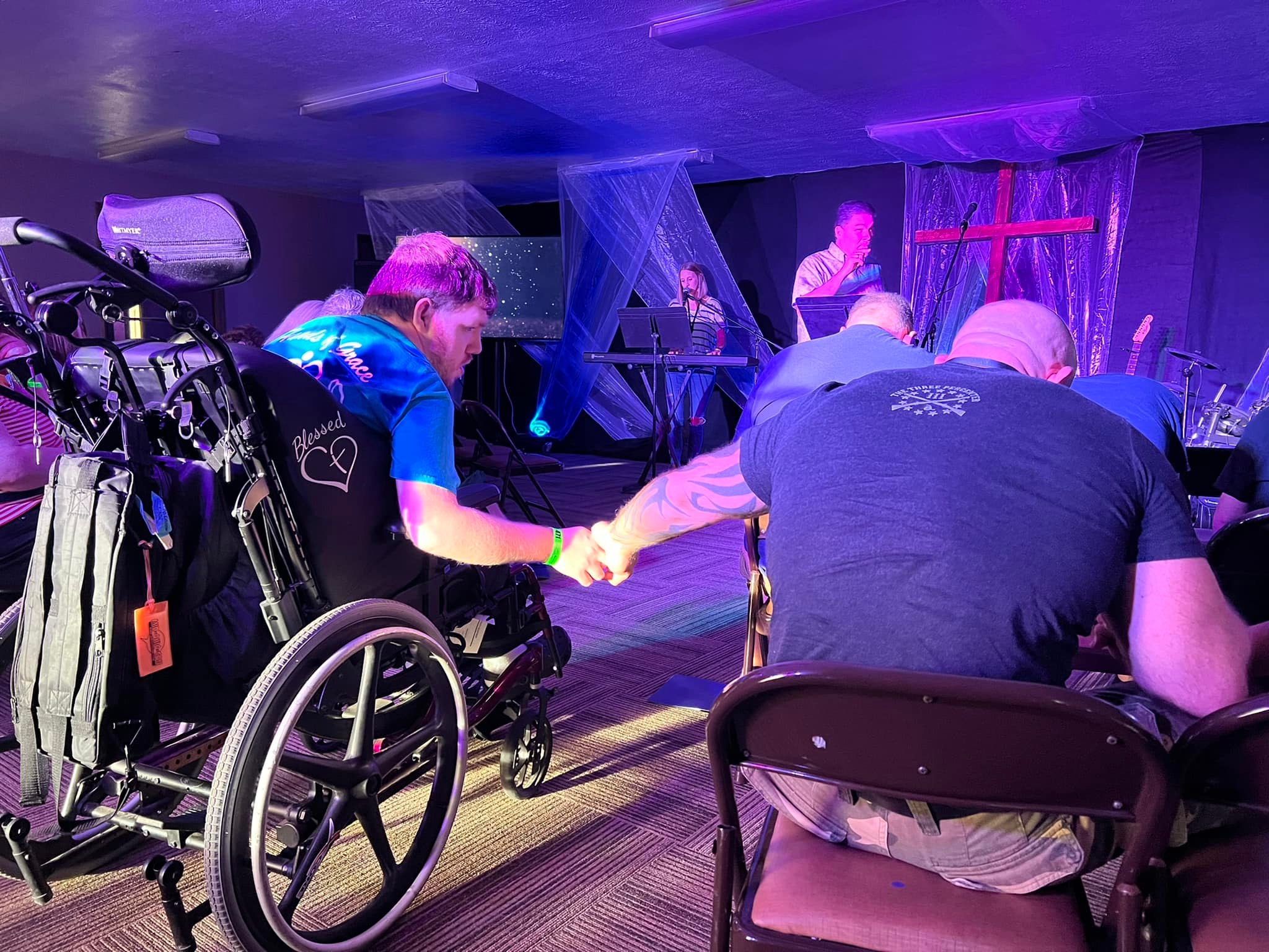 Two men praying, one using a wheelchair