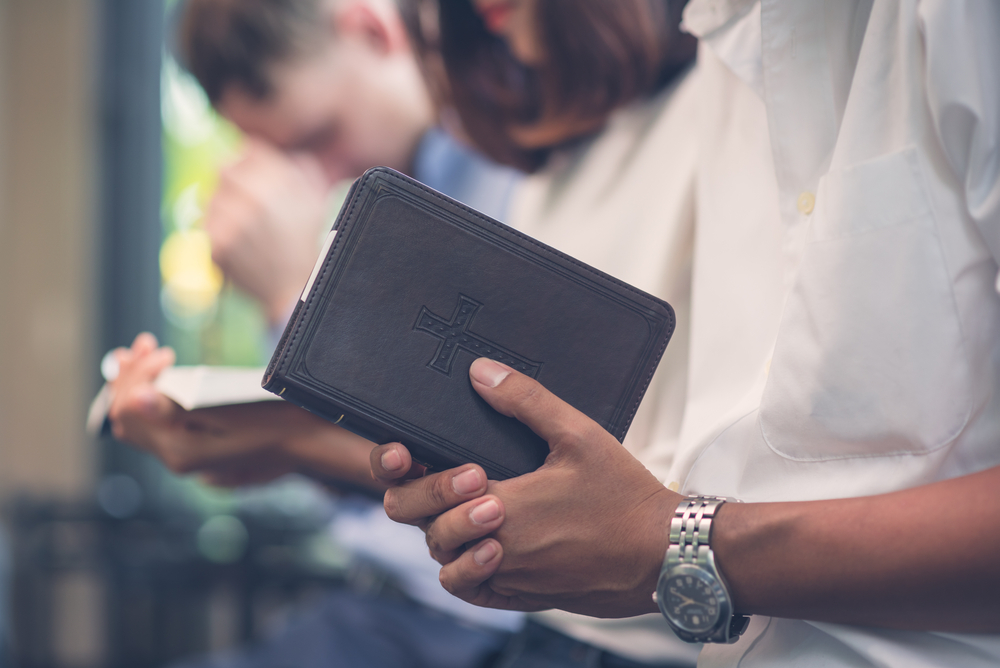 A number of people praying and studying bible