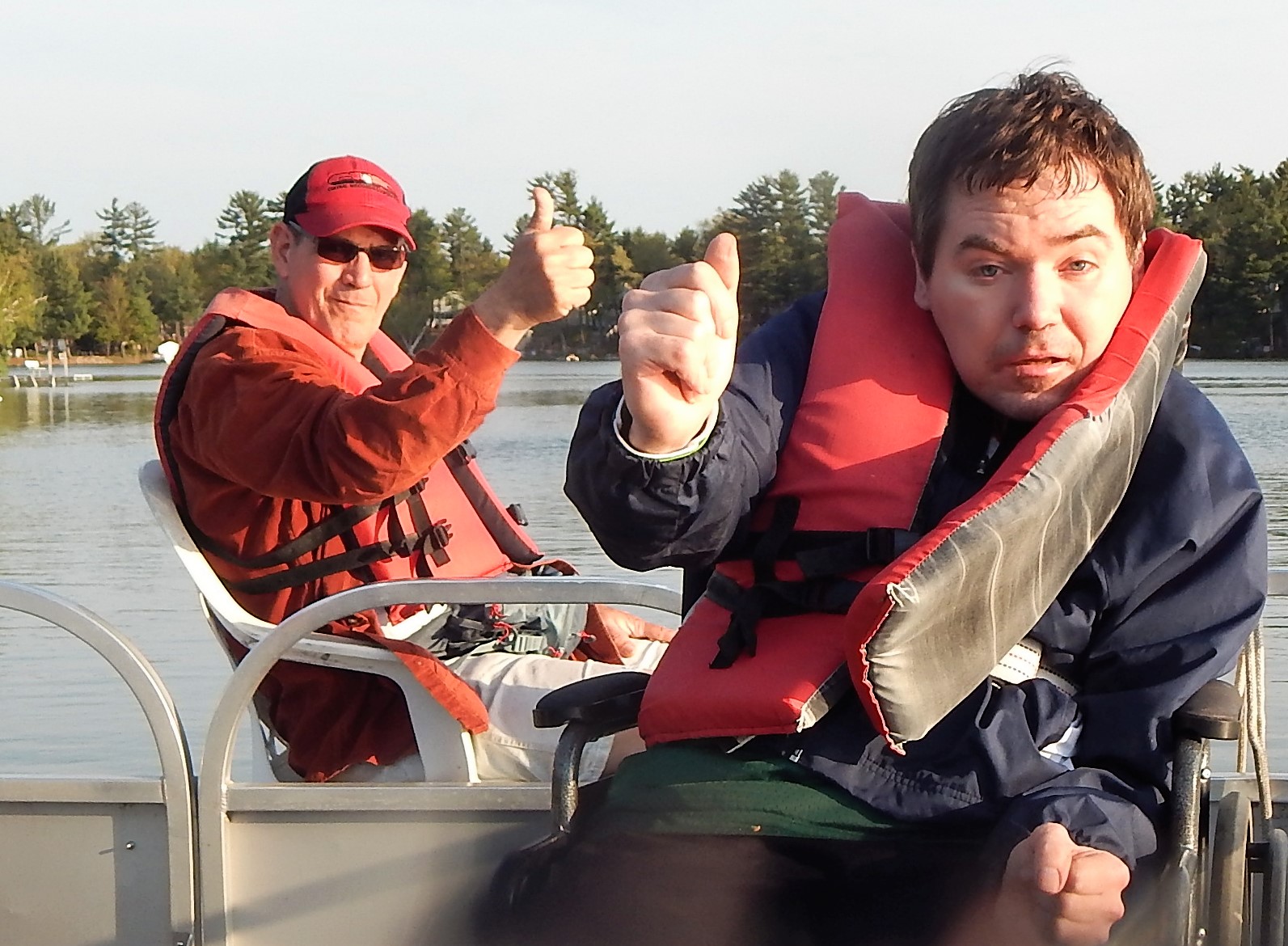 Two men in a pontoon boat with thumbs up