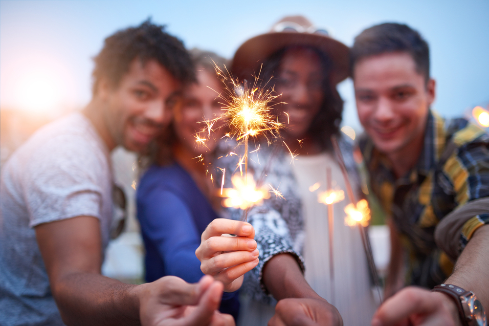 4 people all holding up sparklers