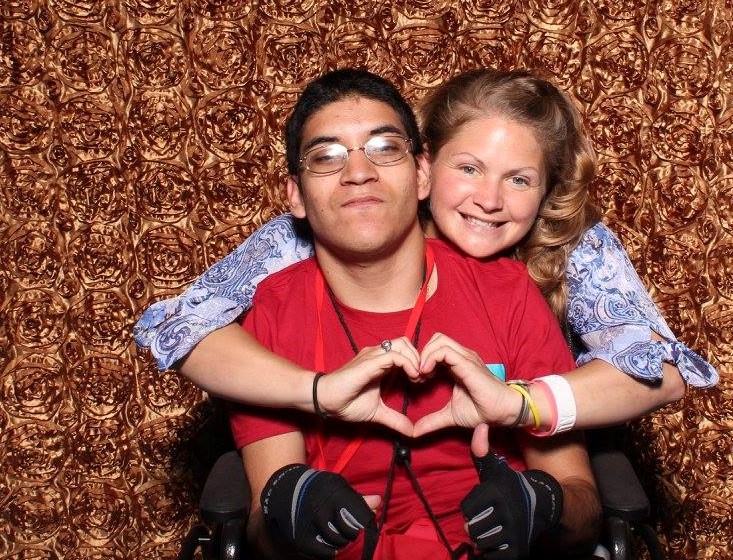 Two people smiling one holding hand in heart shape