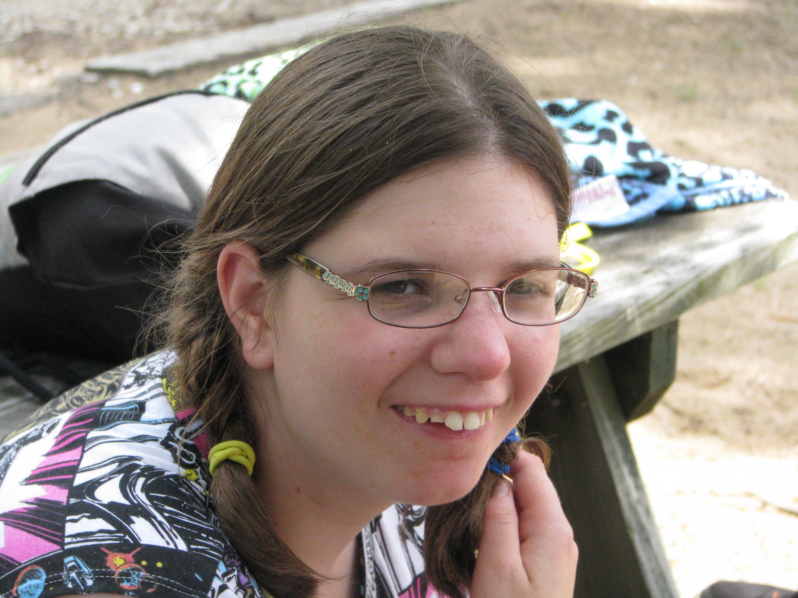 Girl outdoors next to picnic table smiling