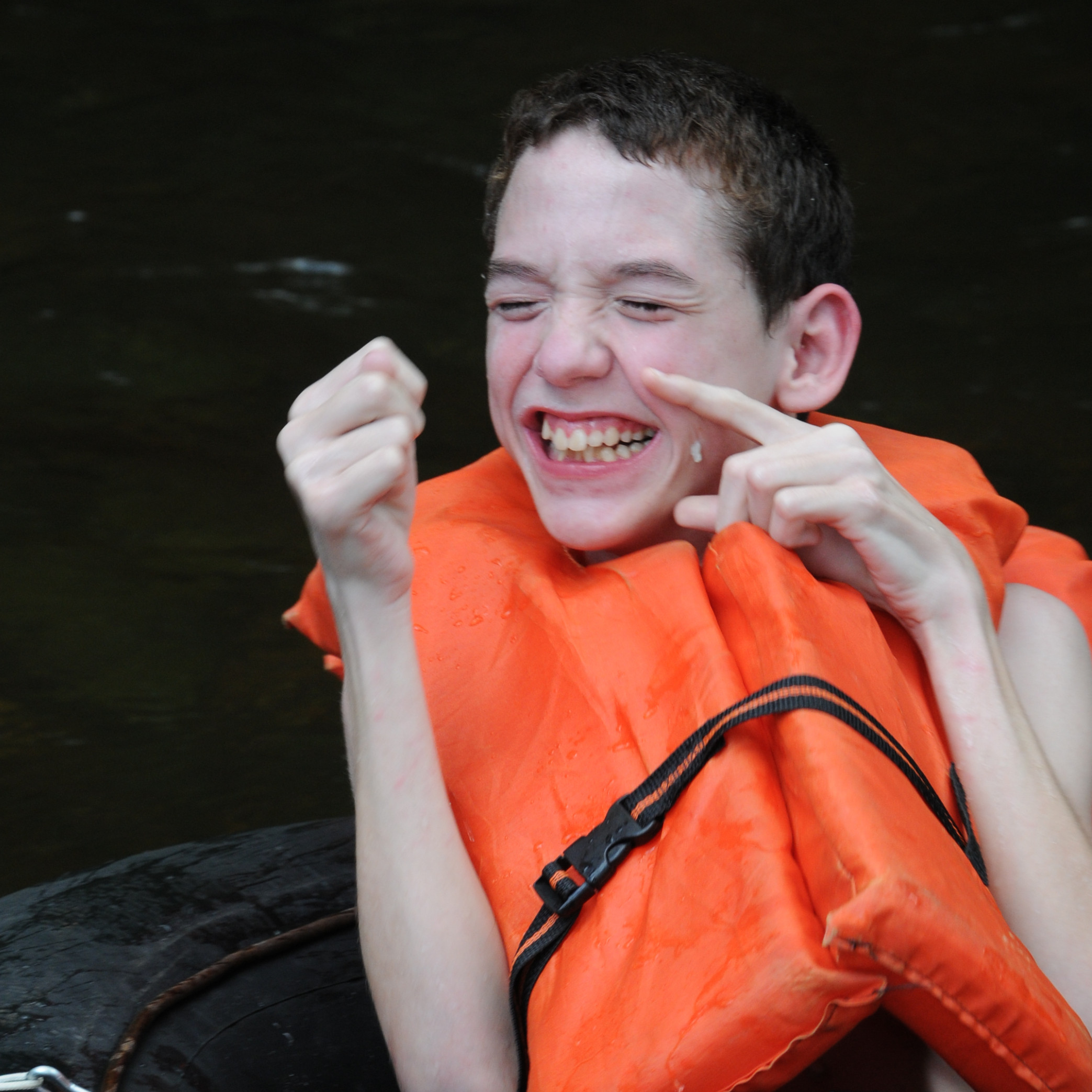 boy on inner tube in water giggling