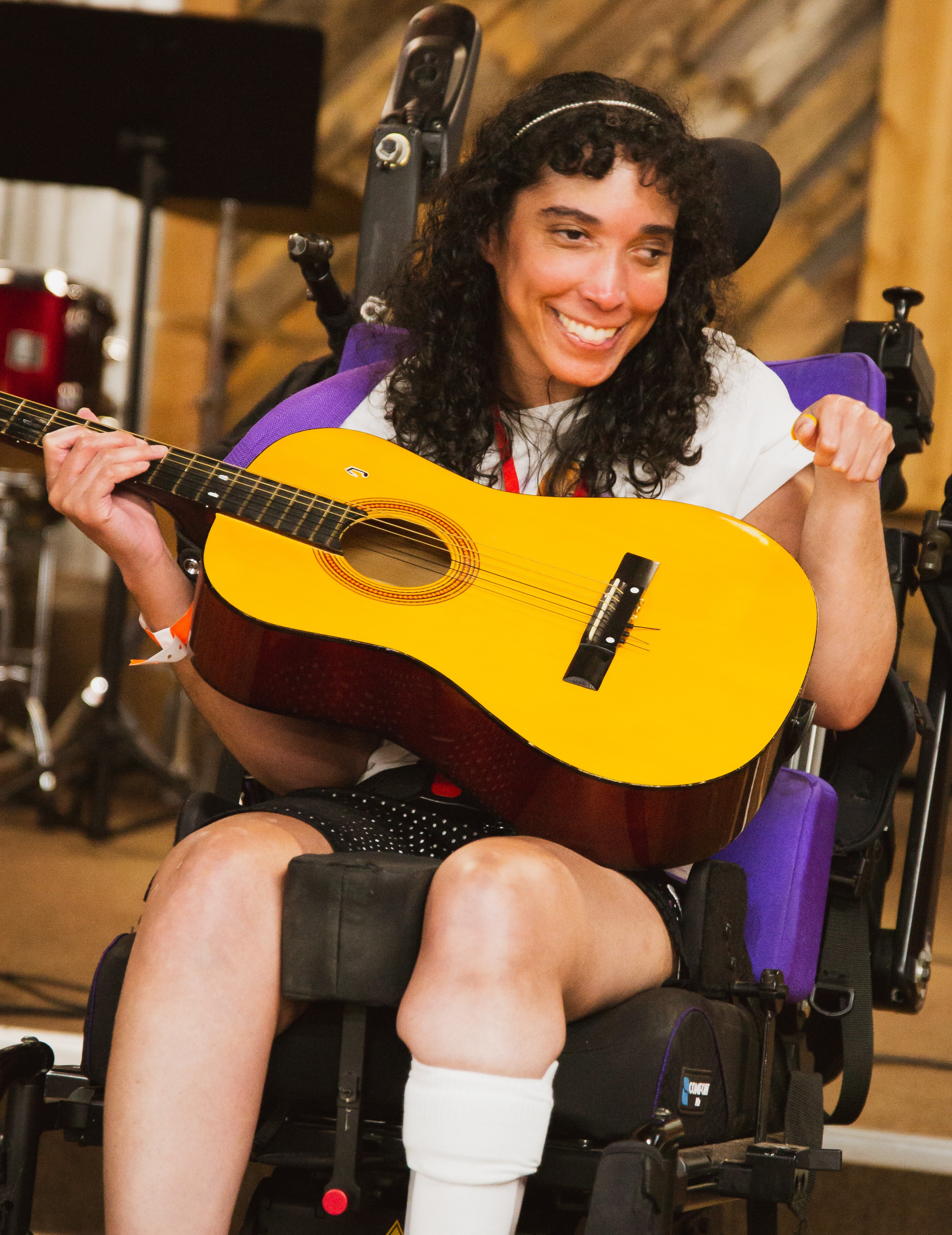 Woman in a wheelchair playing a guitar.