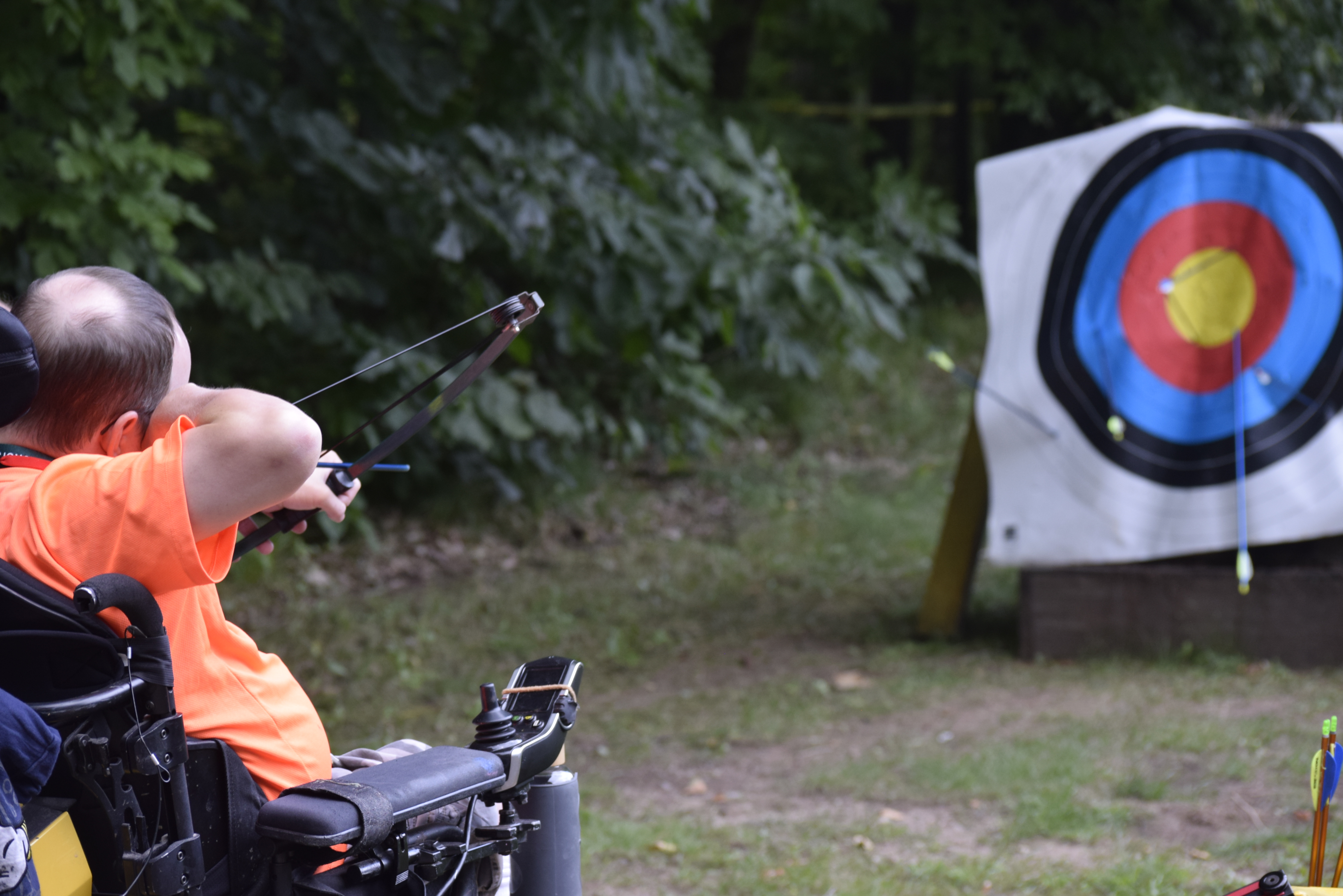 Man sitting in a wheelchair while shooting at an archery target