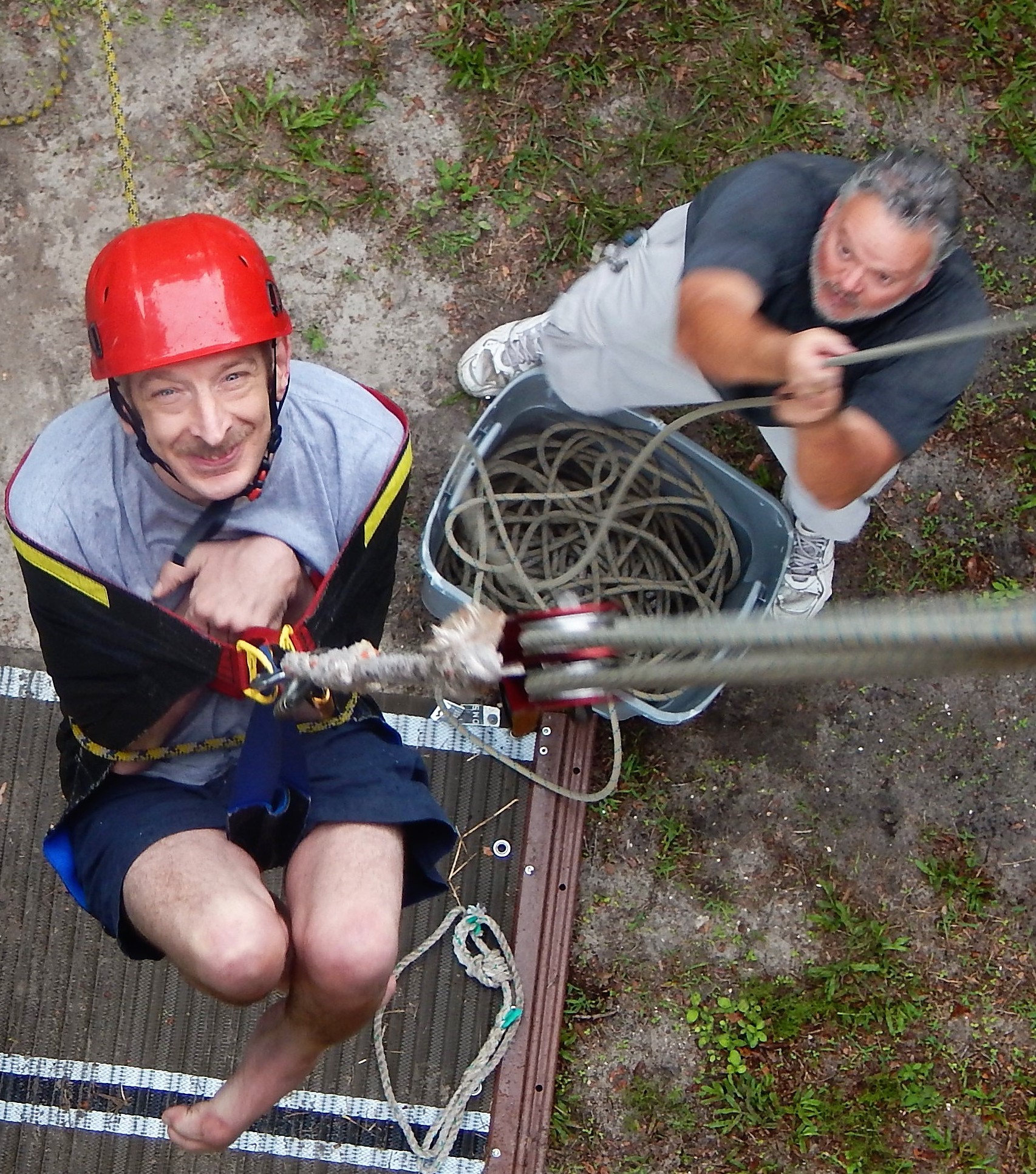 A person with an obvious physical disability being pulled up a climbing wall