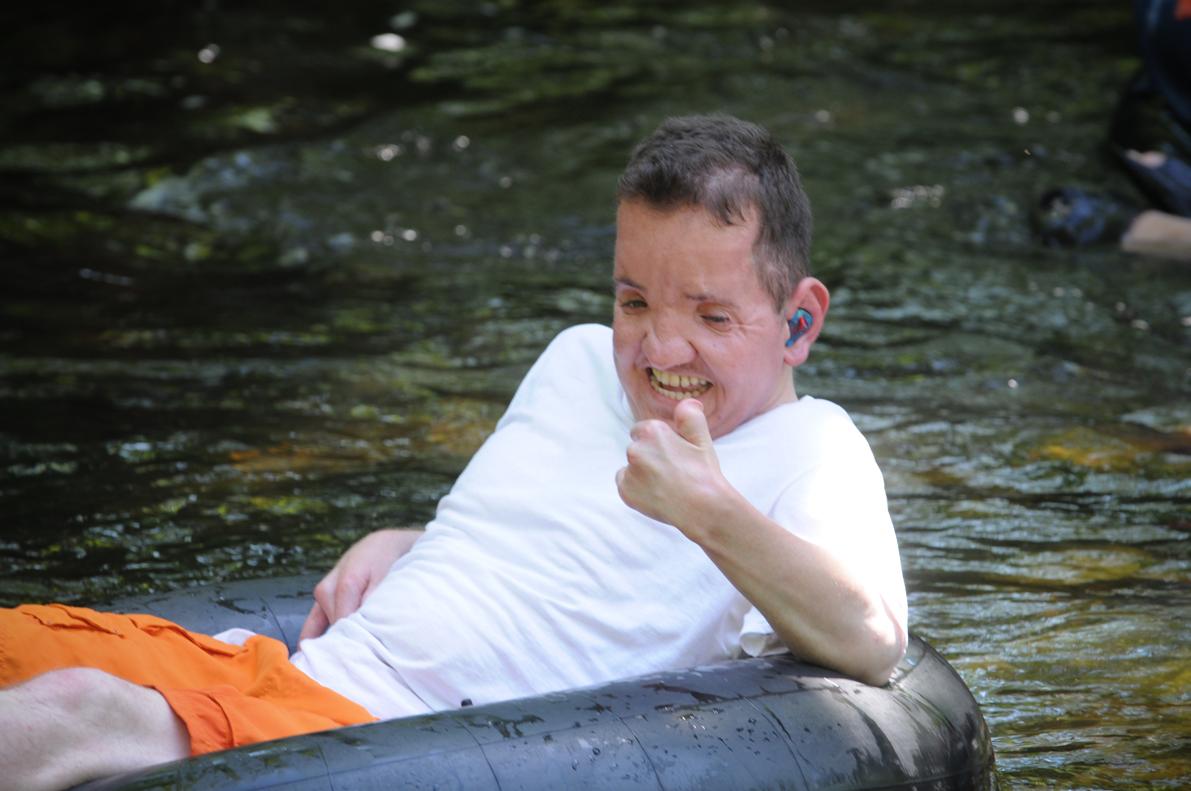 Man with a disability in an inner tube trying to give thumbs up to camera