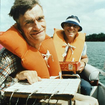 Two men on a boat on a lake smiling