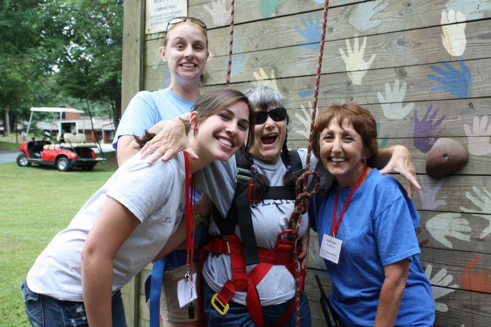 Addie, Ann, Brittany, and another woman standing in front of climbing wall 